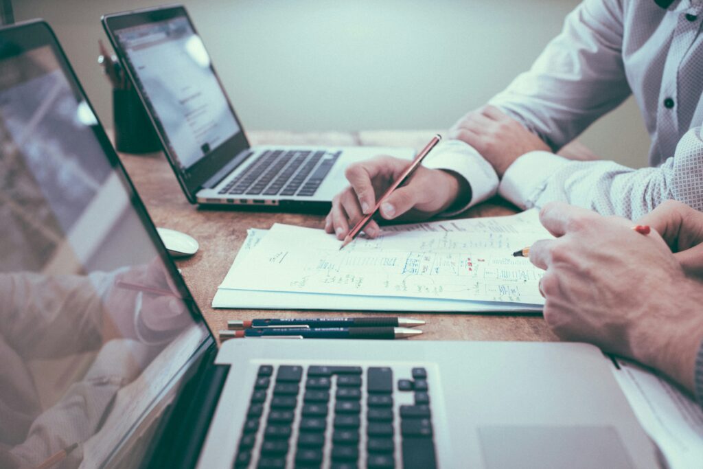 employees taking notes at desk with laptops